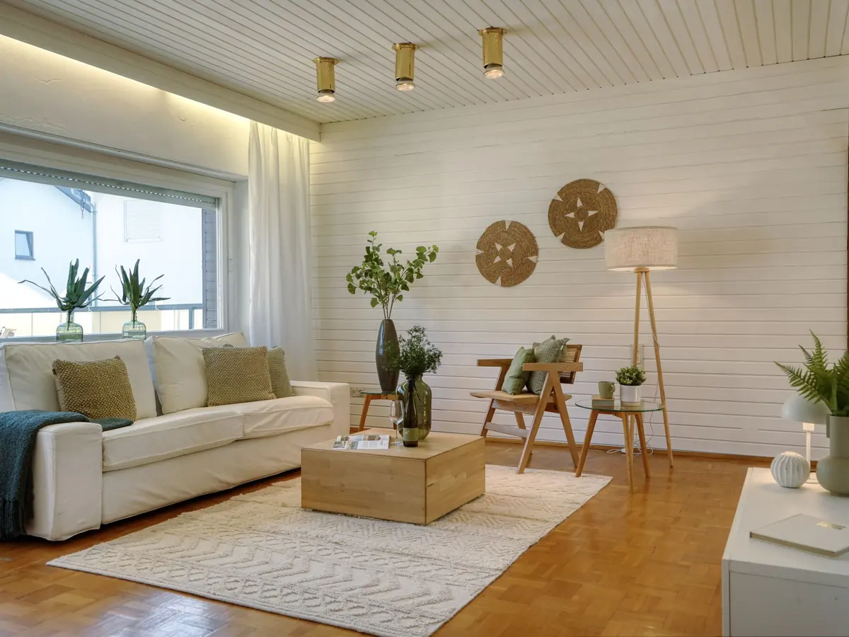 Nachher: helles Wohnzimmer mit heller Couch, Holztisch und Teppich