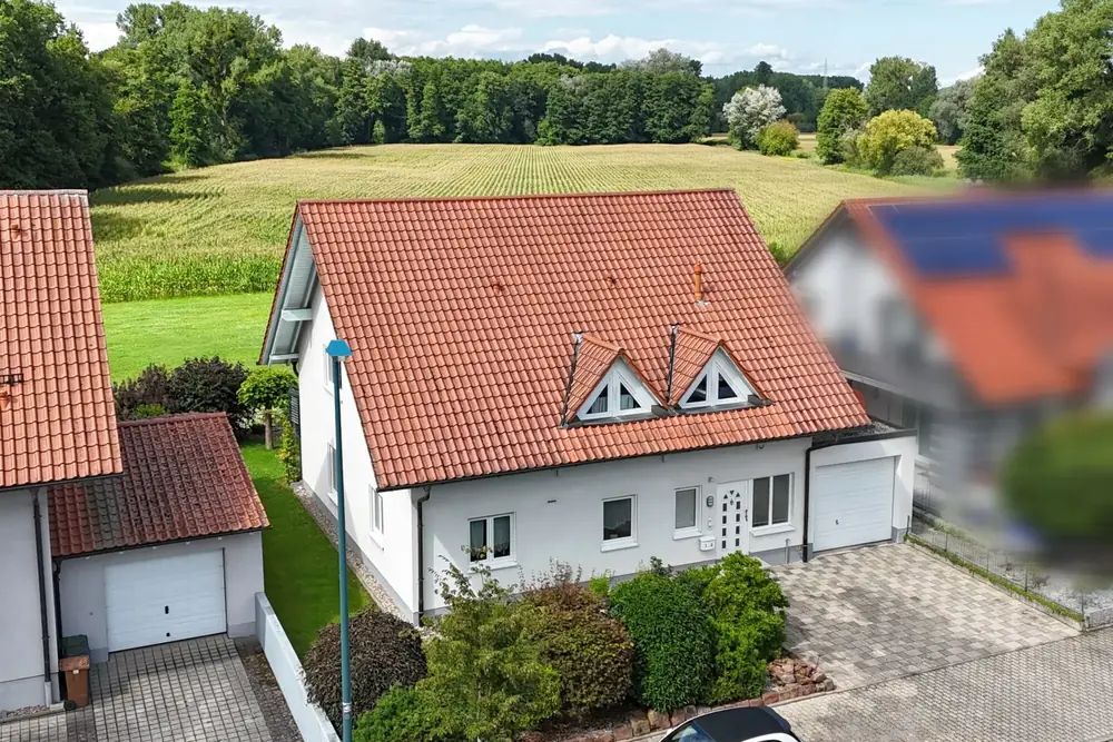 Luftaufnahme eines Hauses am Ortsrand, dahinter offene Felder