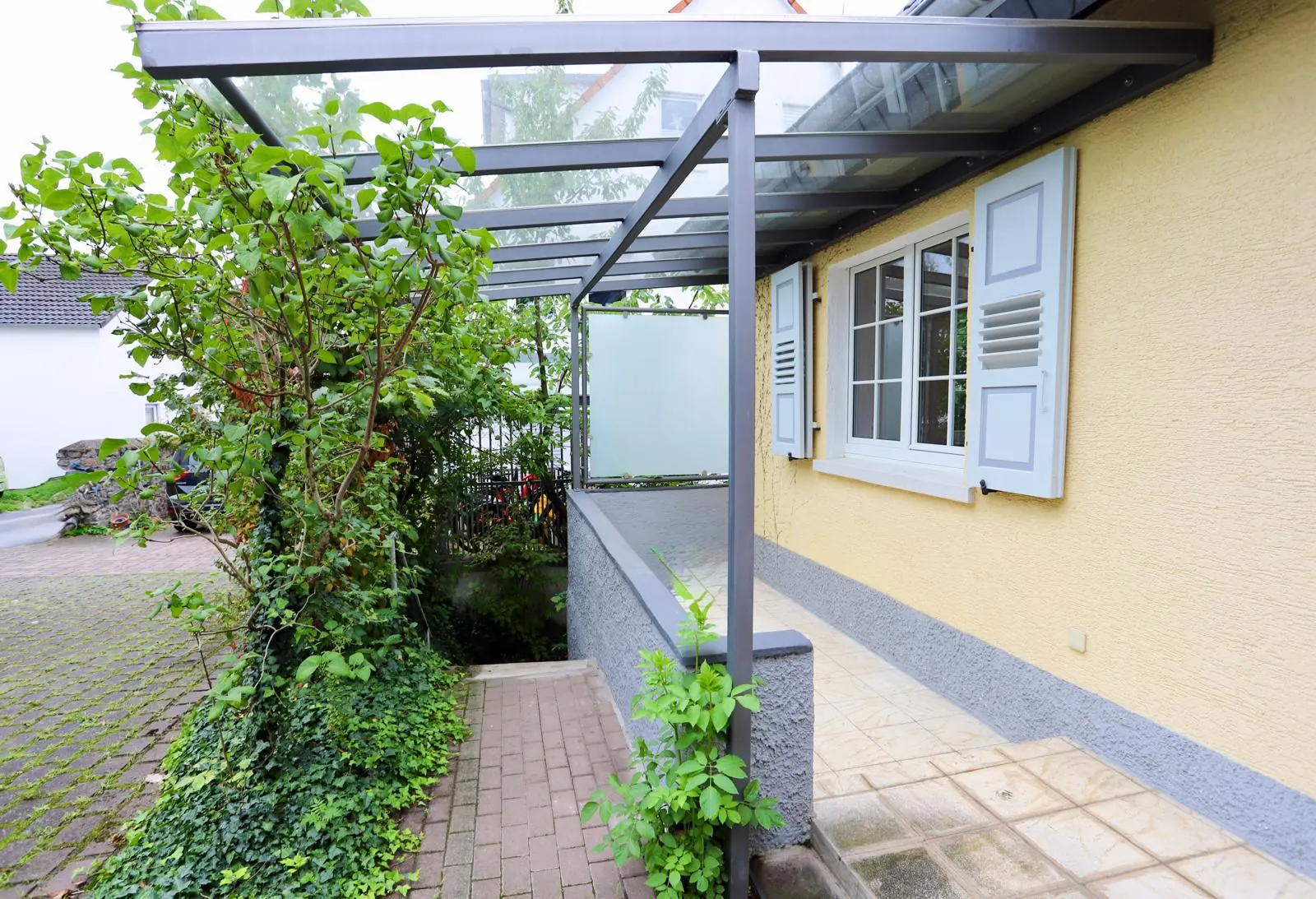 Eingangsbereich mit Glascarport und Zugang zum Garten